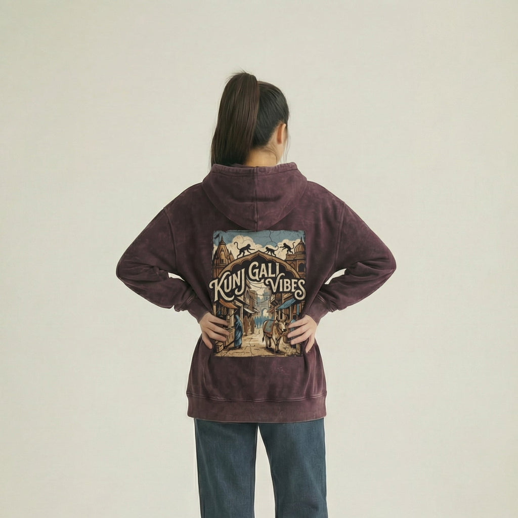 Person wearing a maroon hoodie with a graphic design on the back, standing against a plain background.