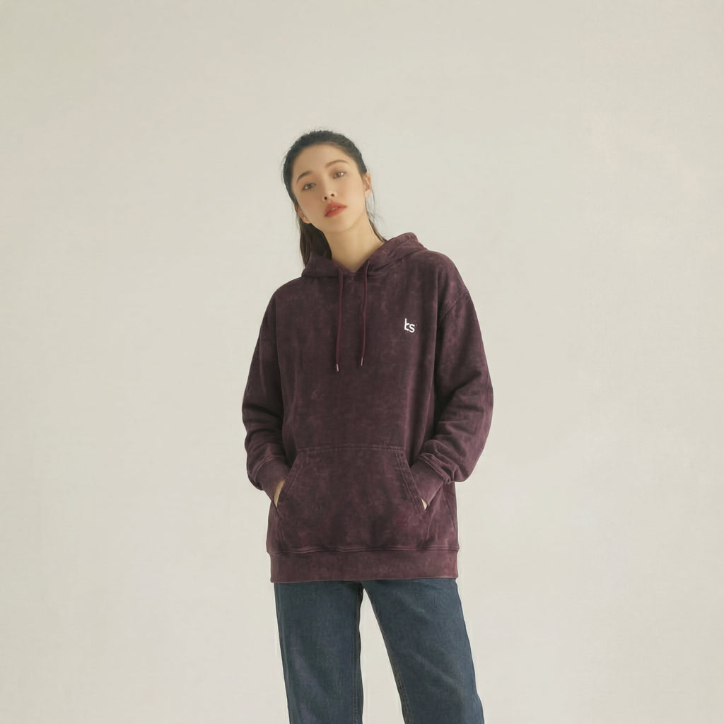 Person wearing a maroon hoodie and blue jeans on a beige background